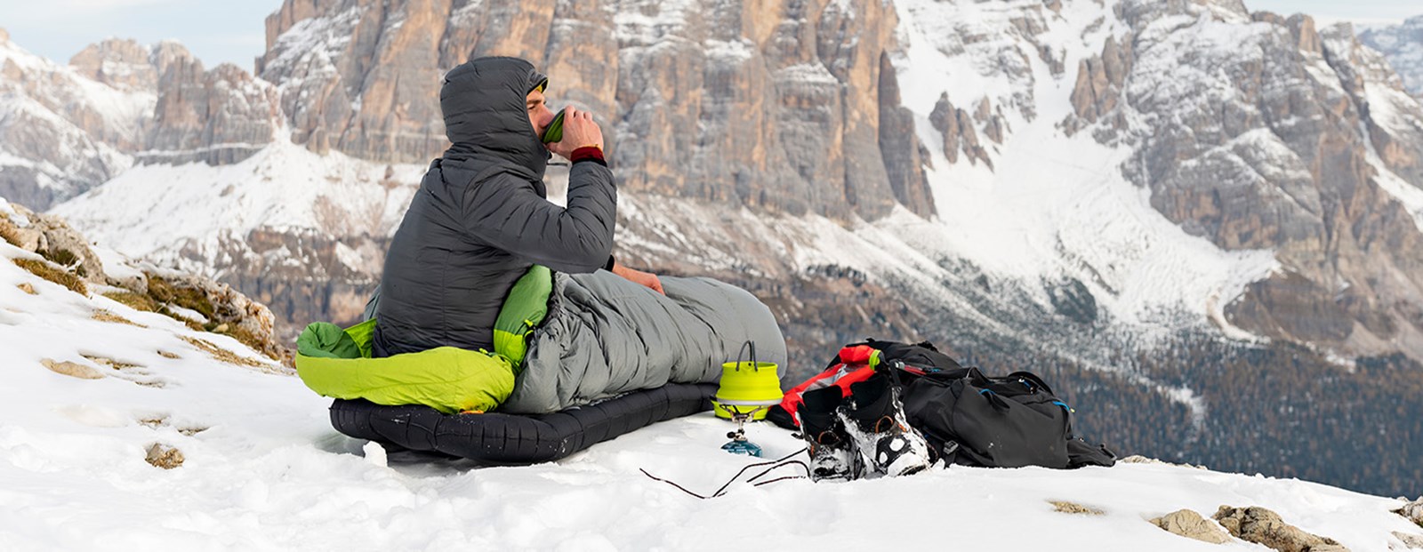Mand der nyder en kop kaffe med en flot udsigt i sin sovepose.