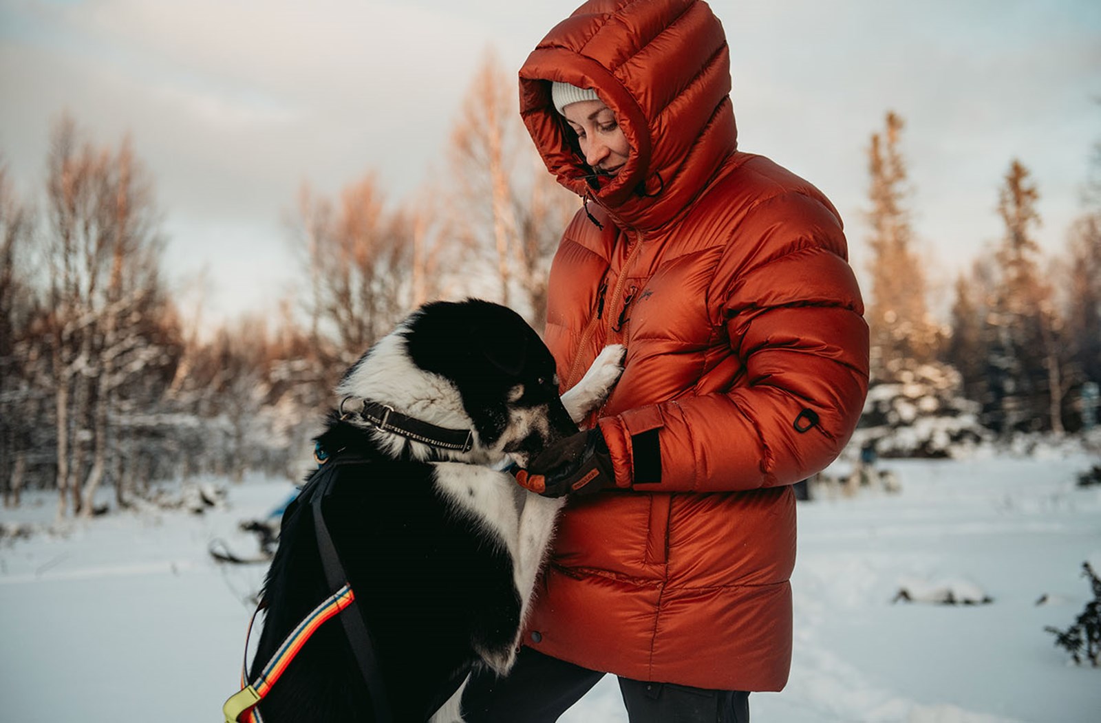 En kvinde i en Lundhags dunjakke, der leger med sin hund.