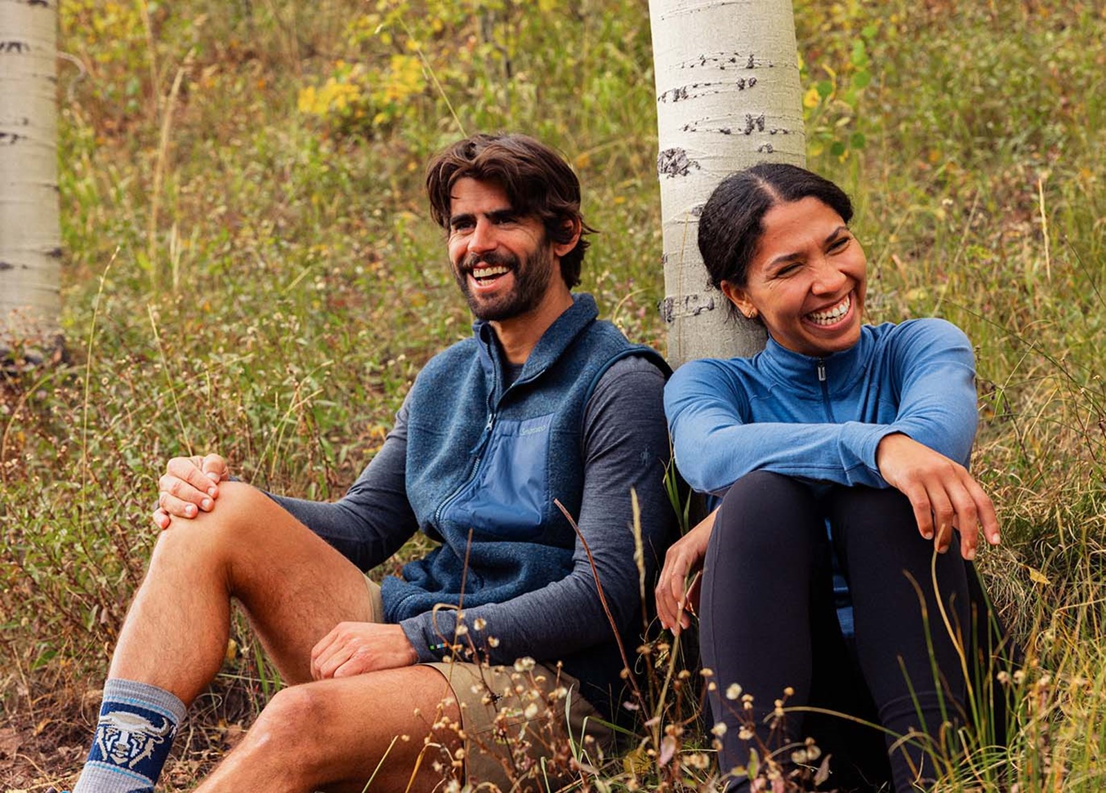 To personer der sidder i græsset iført SmartWool.