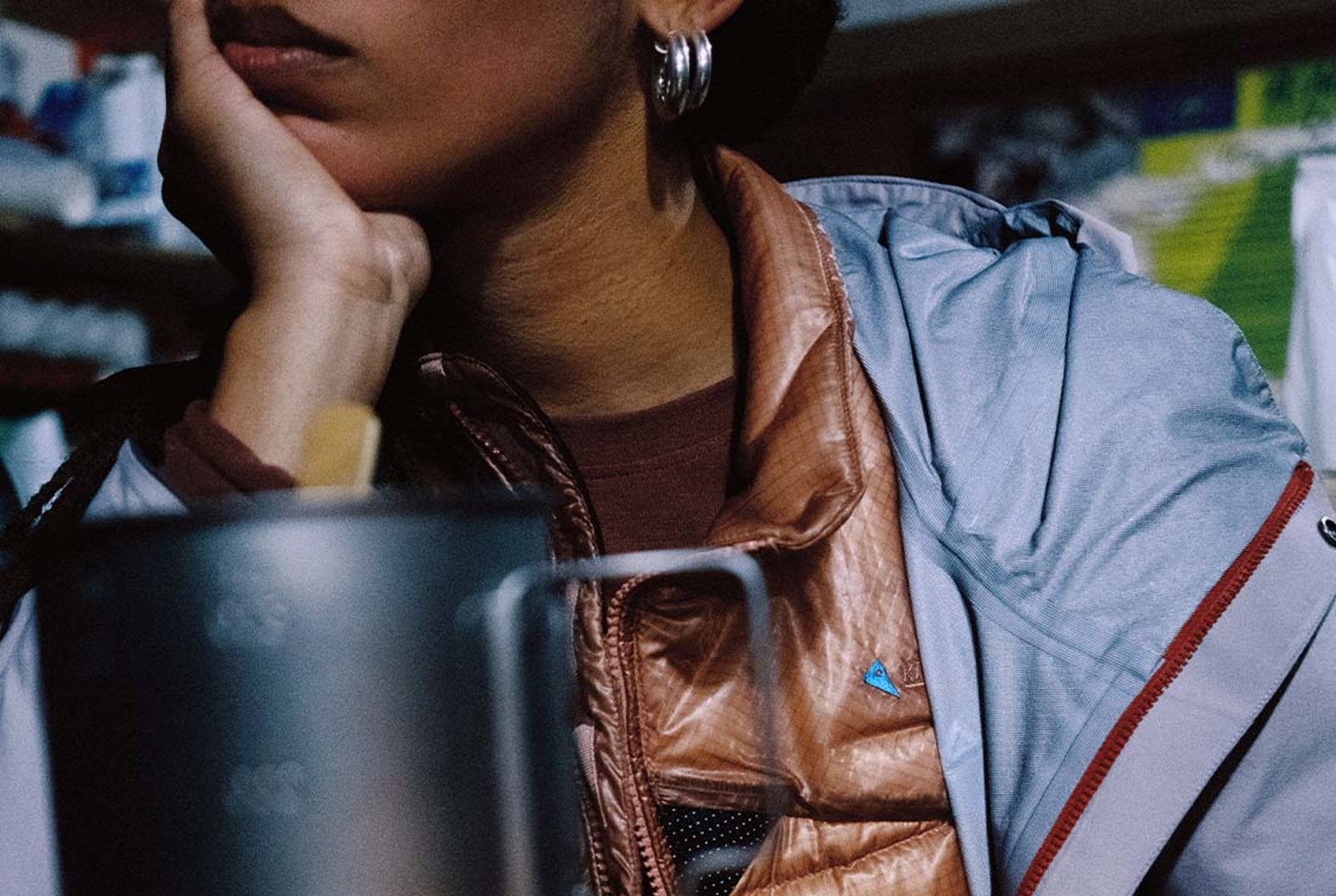 En kvinde der laver mad iført en dunjakke med en skaljakke over.