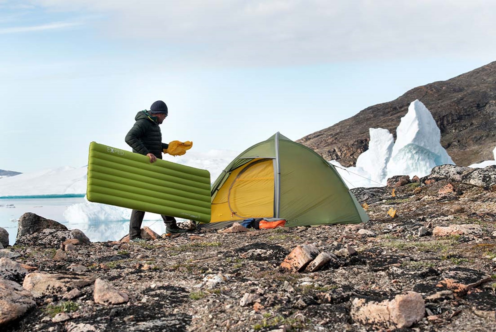 Mand er ved at bære sit oppustede liggeunderlag ind i sit telt.