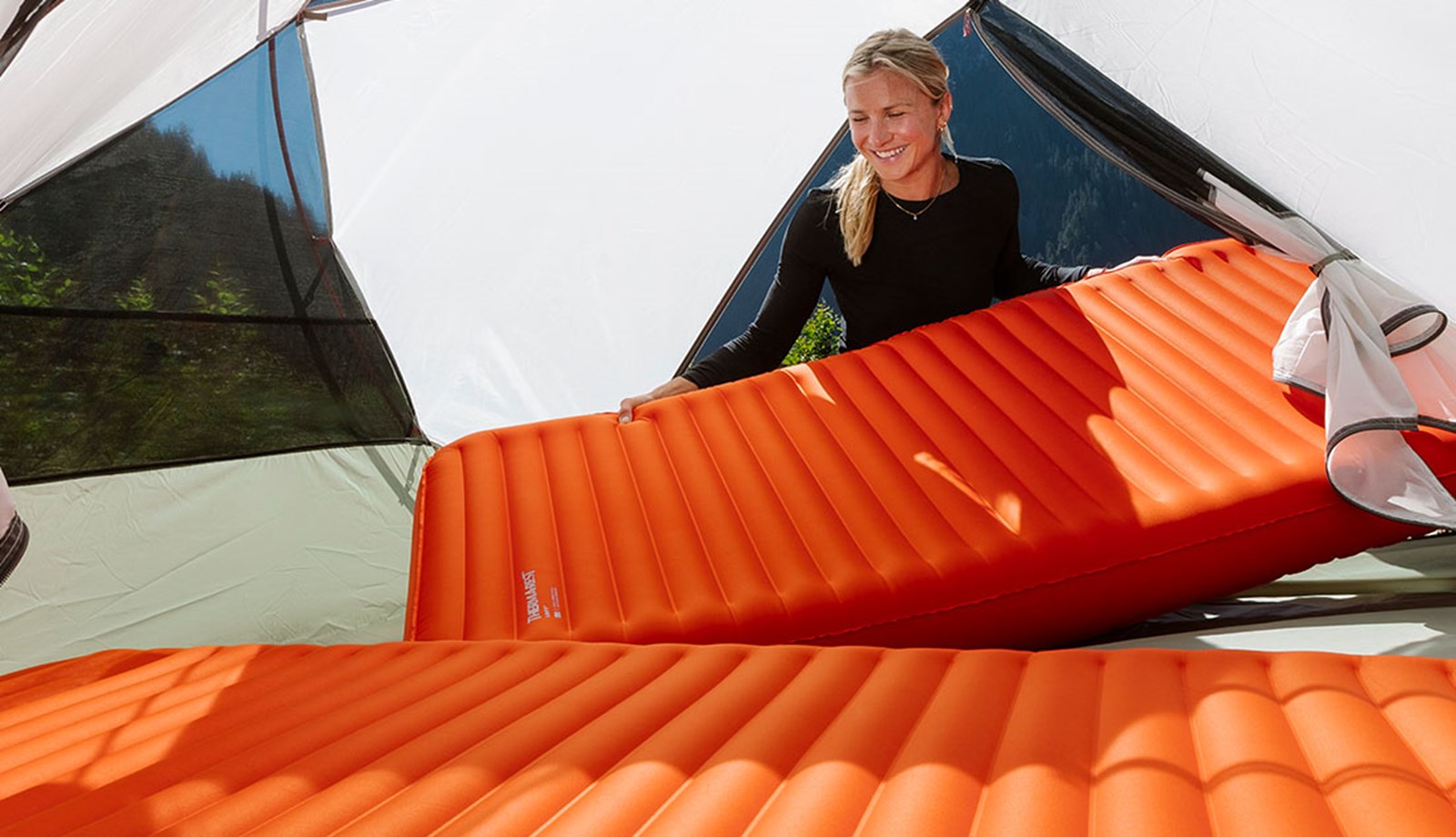 Kvinde lægger sine liggeunderlag ind i teltet.