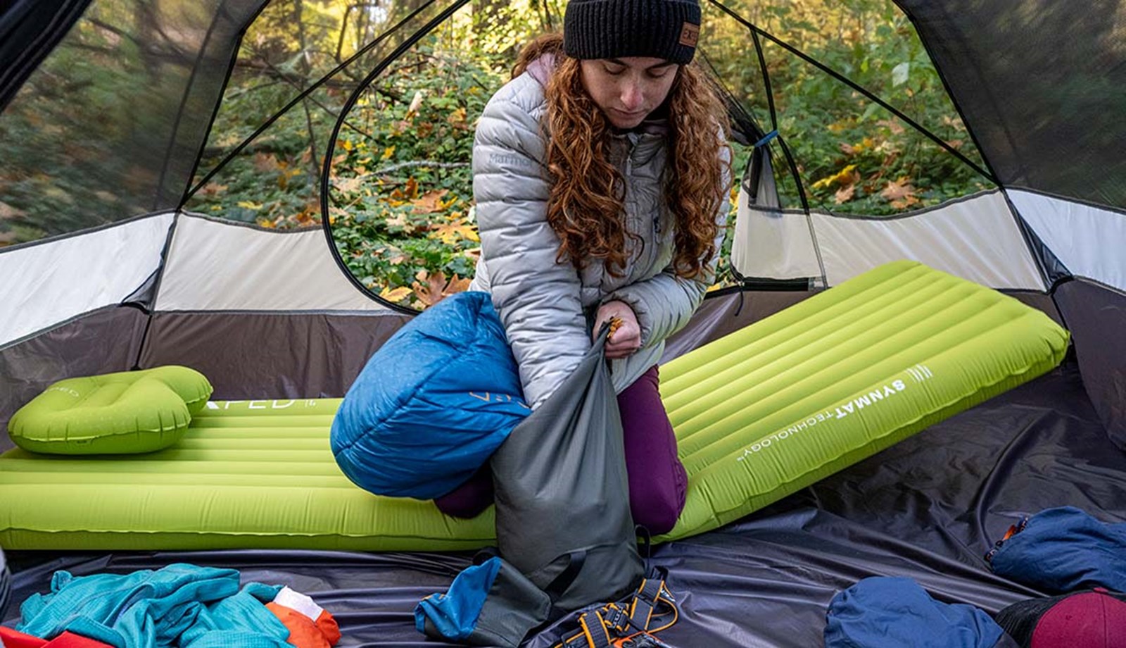 Kvinde pakker sin camp ned, mens hun sidder på et Exped liggeunderlag.