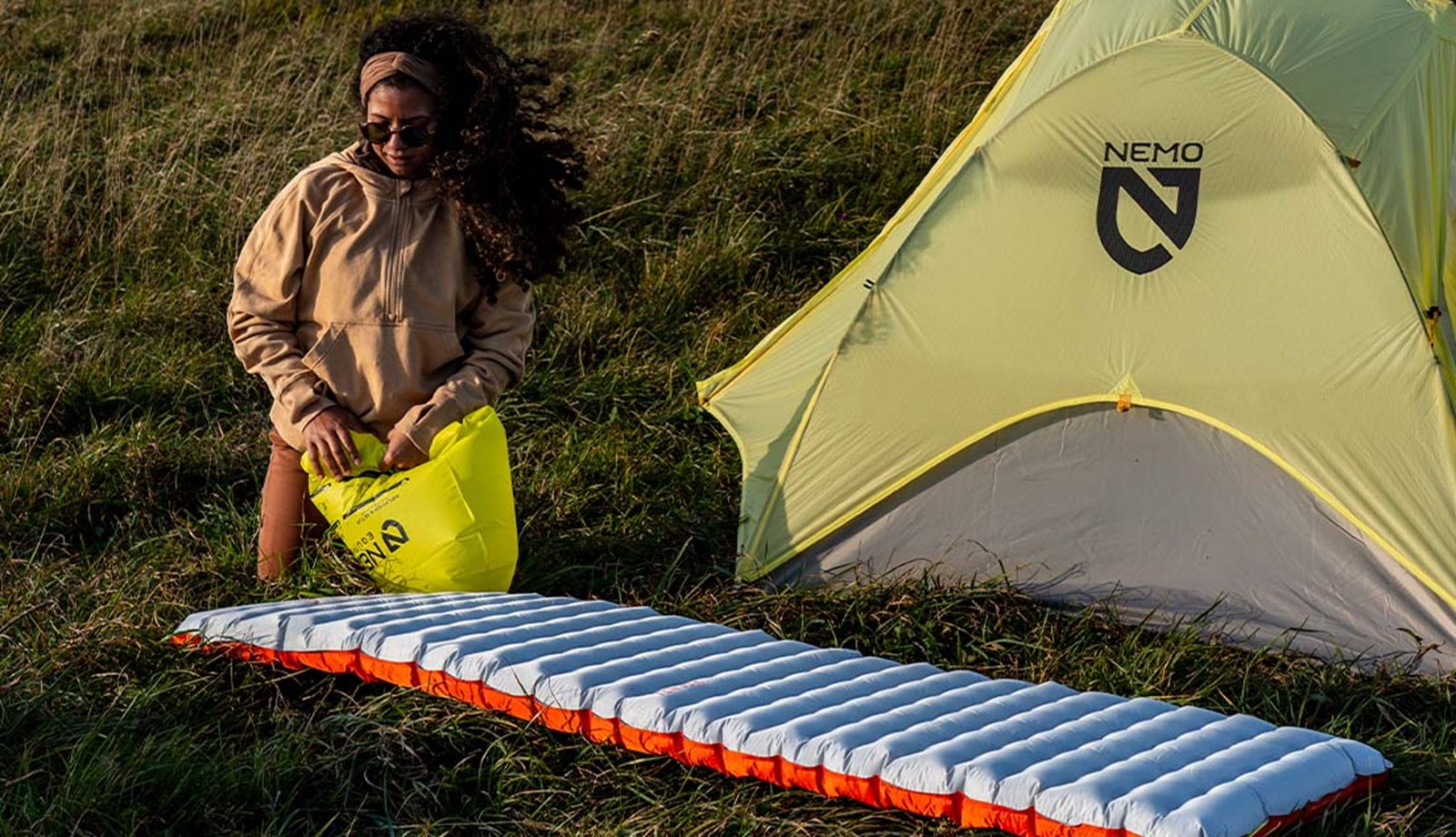 Kvinde puster sit Nemo liggeunderlag op med den medfølgende pakkekpose.