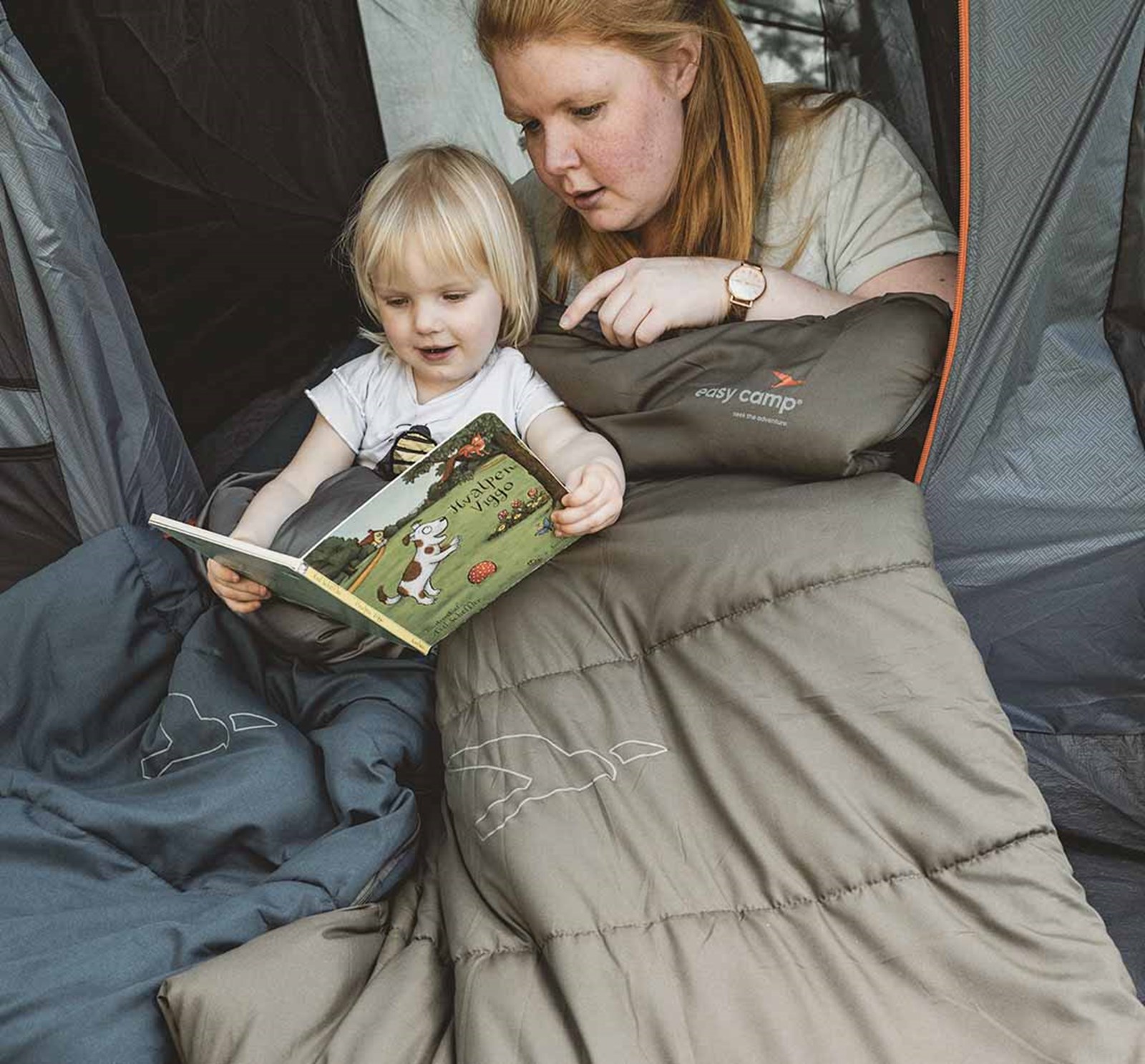 En mor og et barn der læser i soveposerne fra Easy Camp.