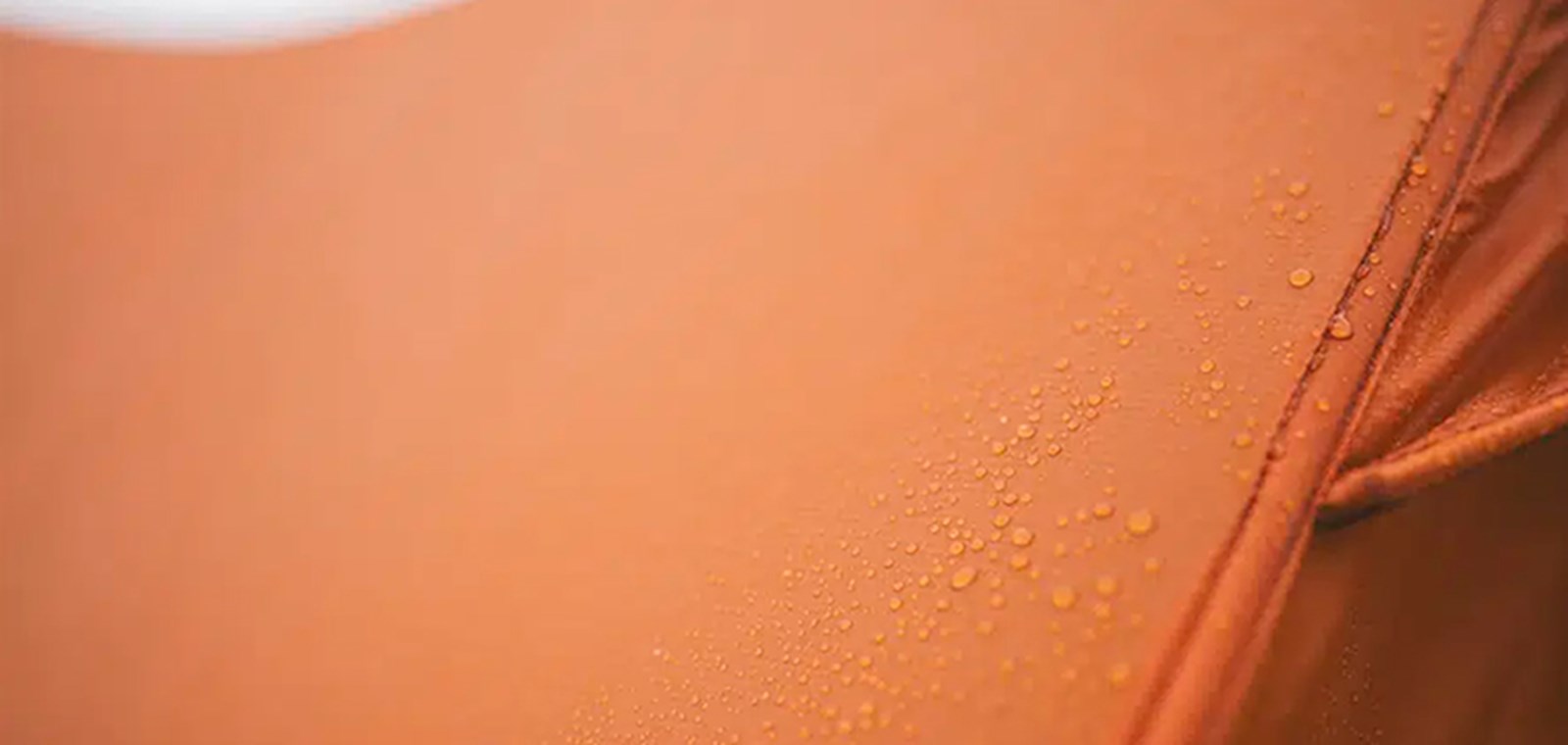 Nærbillede af teltets ydermateriale med regndråber på.