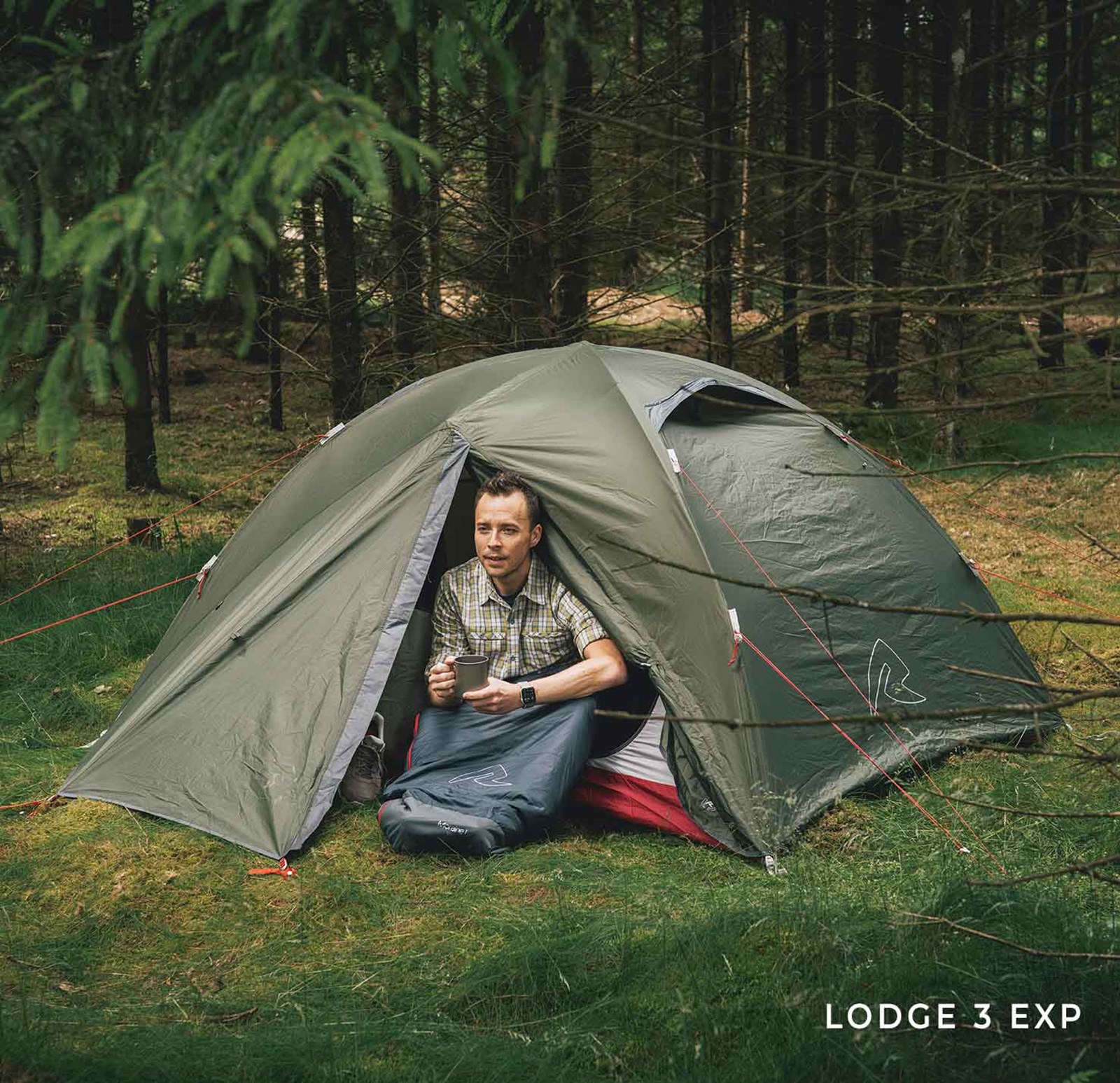 Mand sidder i telt i skoven.