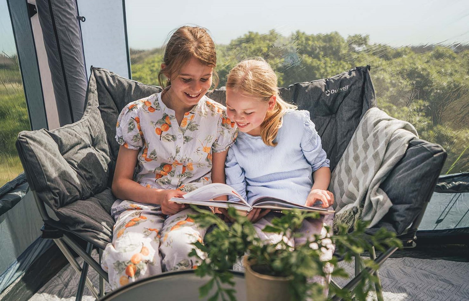 To piger der kigger i en bog sammen inde i et Outwell-telt.
