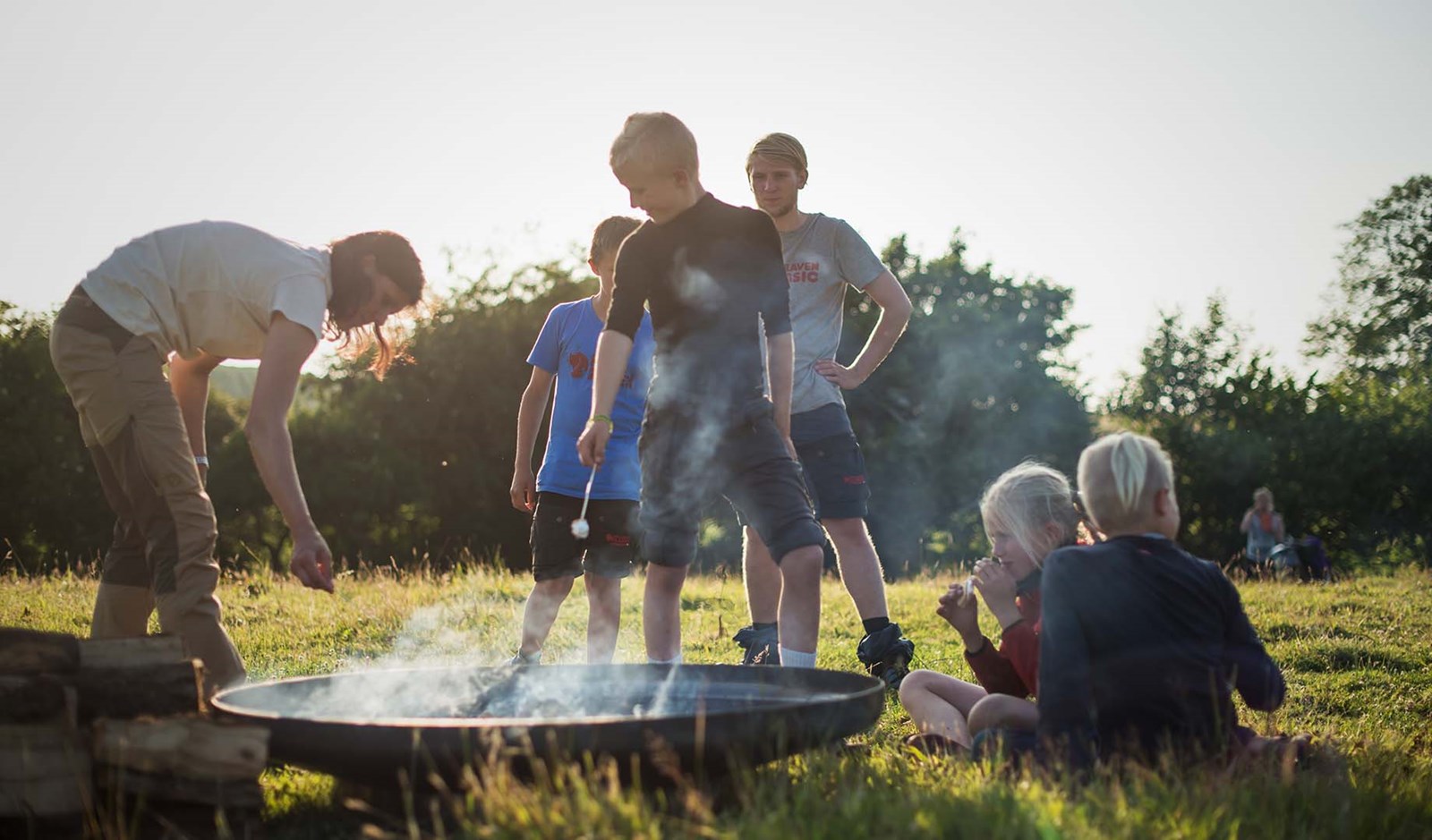 Børn og unge rundt om et bål.