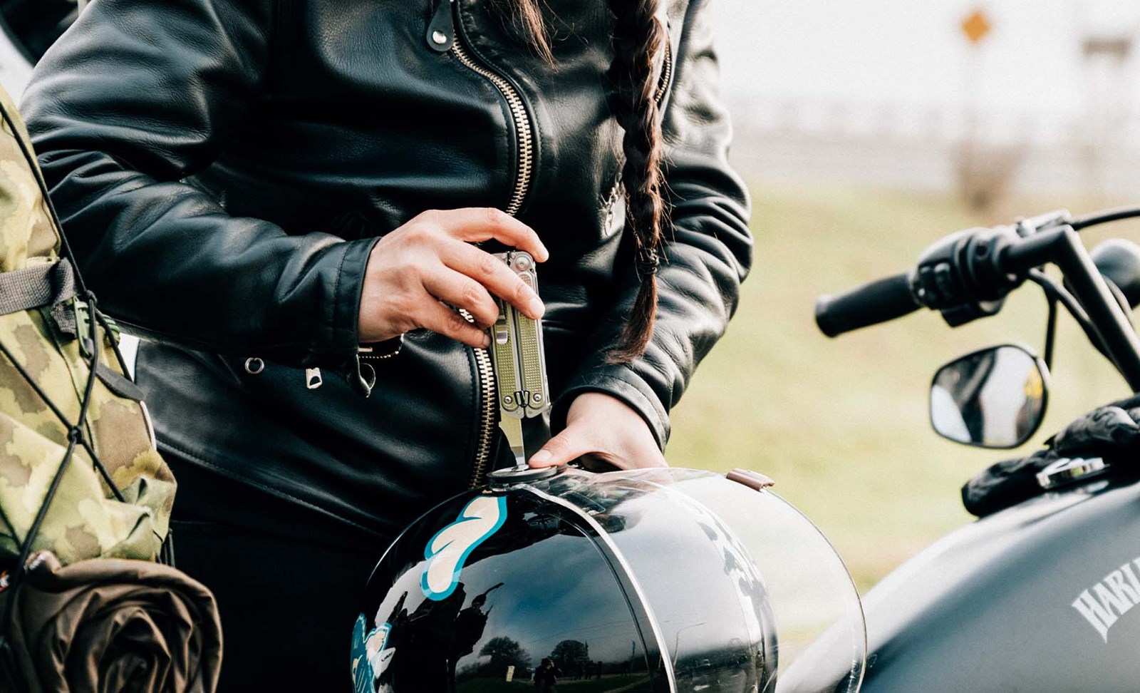 Person der bruger multitool til at ordne deres motorcykelhjelm.