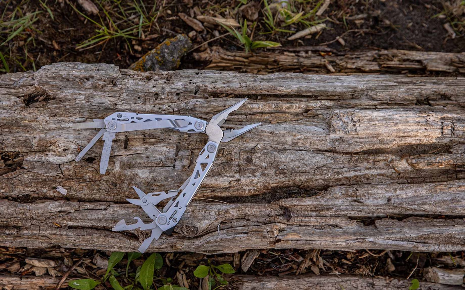 Udfoldet multitool på en træstamme.