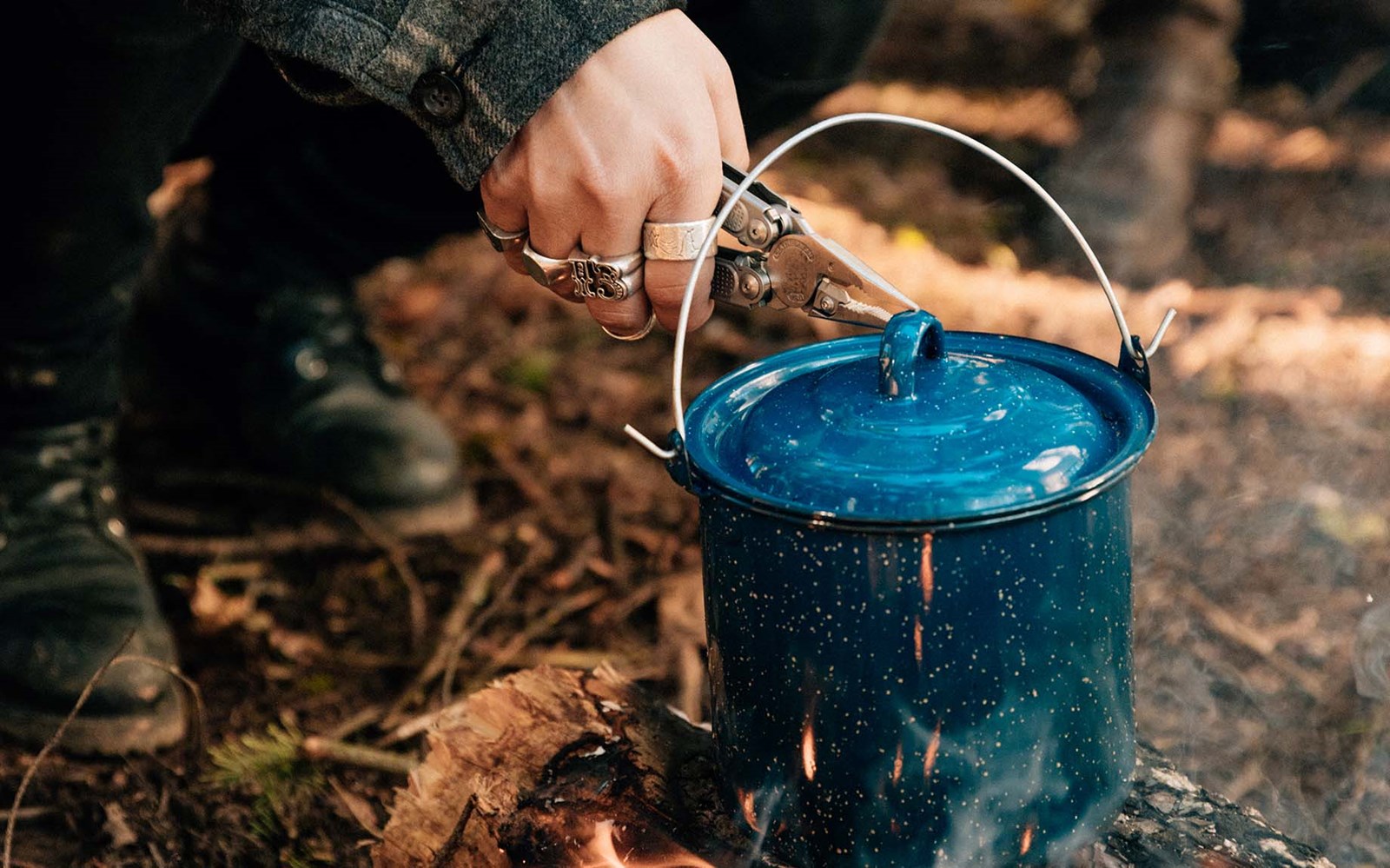 Multitool der bliver brugt til at løfte låget på en gryde over bål.