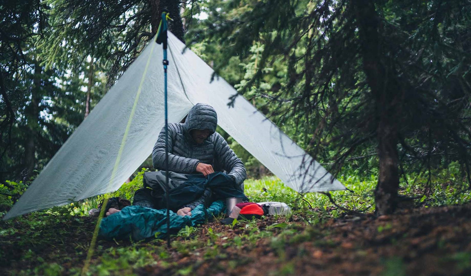 Person der har slået en tarp op ved hjælp af sien vandrestave.