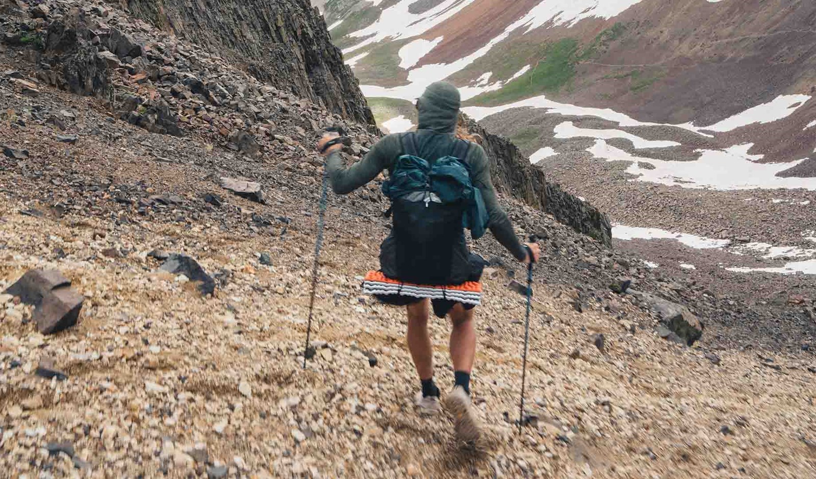 Person der er på ved ned af et bjerg med sine vandrestave.