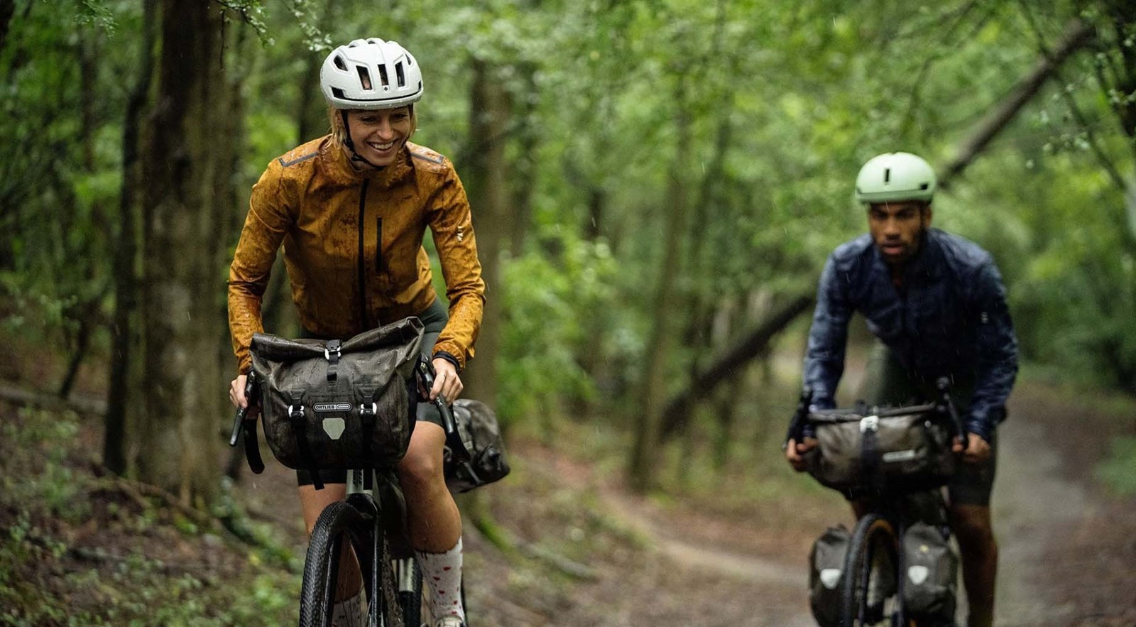 To personer på cykel i en skov med oppakning.