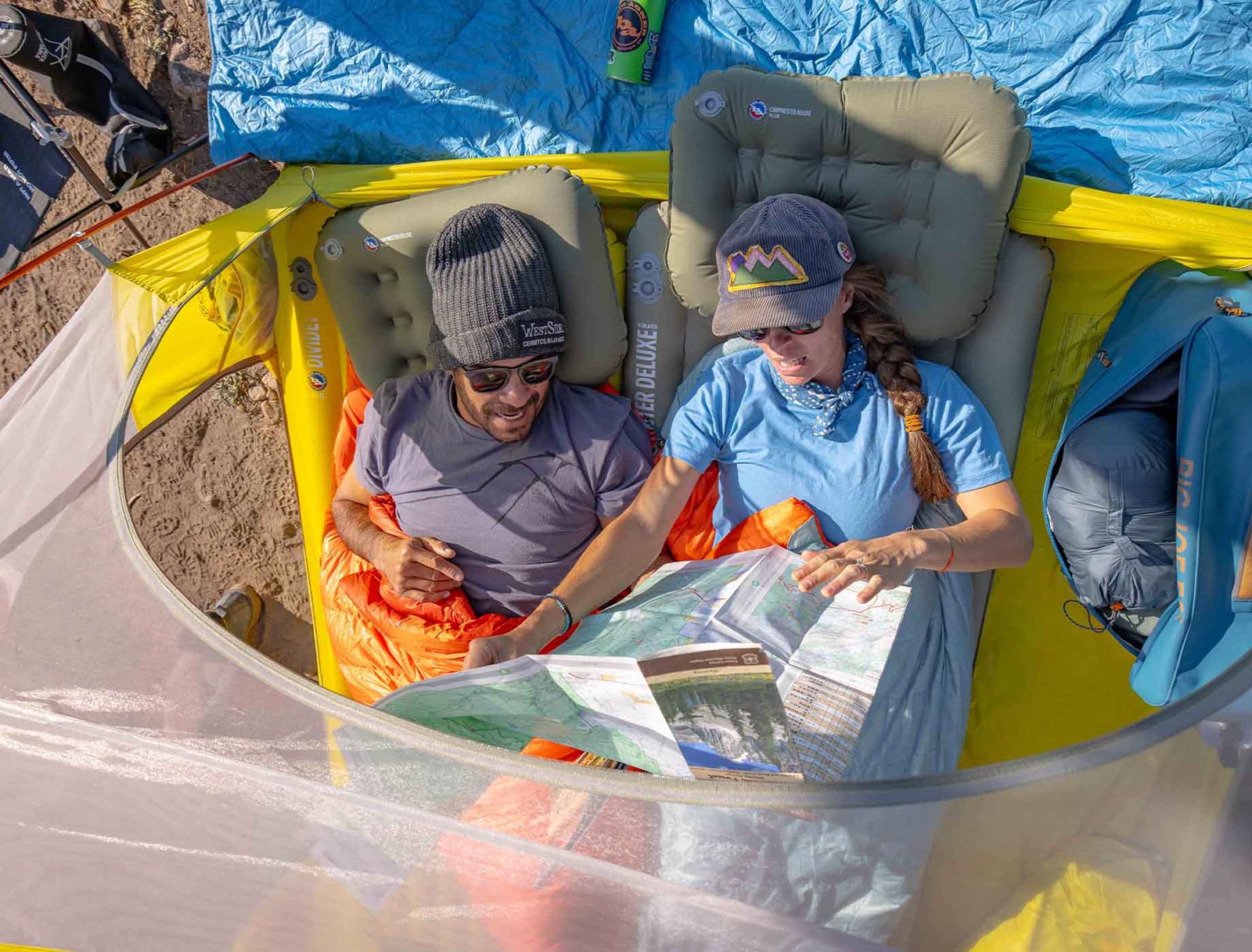 To personer set oppefra der ligger i et Big Agnes telt.